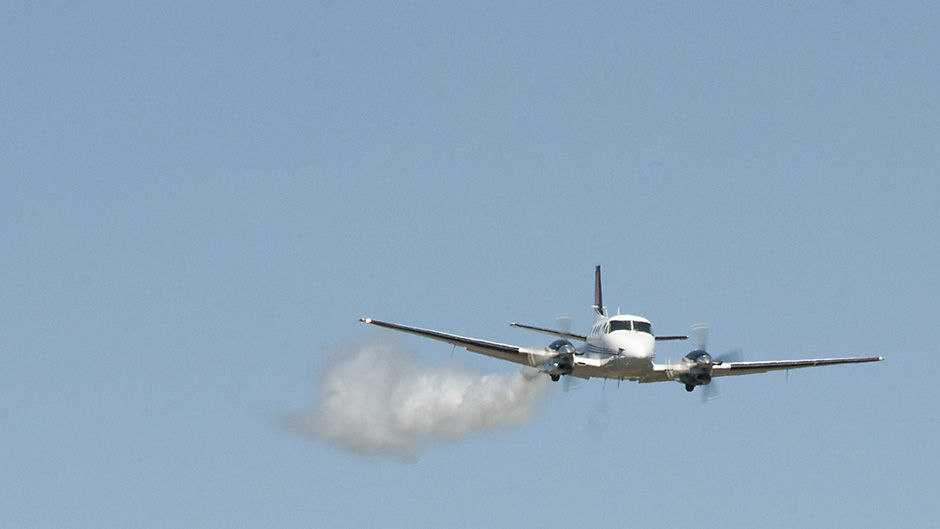 plane flying with smoke coming off one engine